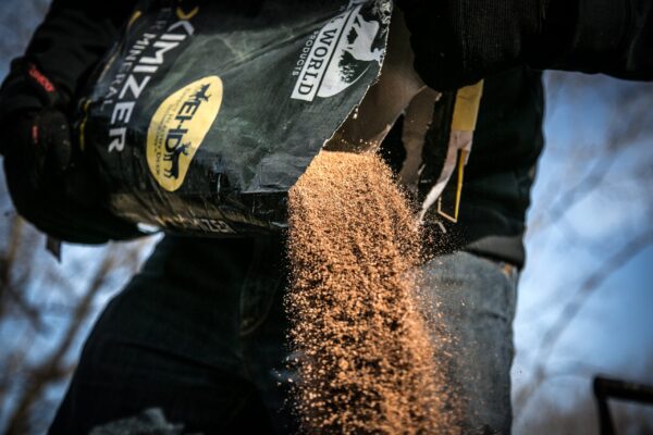 man dressed in black dumping a bag of animal feed